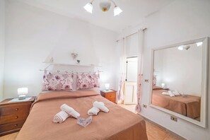 A hotel room with a bed, a nightstand, a mirror, and a window with curtains. - Rusciu Te Lu Mare Apartment With Terrace & Garden (Porto Cesareo)