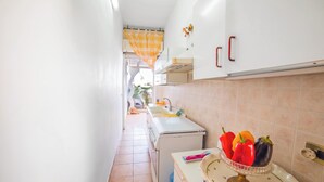 A narrow kitchen with white cabinets, a white refrigerator, and a tiled backsplash. - Rusciu Te Lu Mare Apartment With Terrace & Garden (Porto Cesareo)