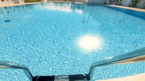 Ein klares, blaues Schwimmbecken mit deutlich sichtbarem Rand und einer Poolleiter, die ins Wasser führt.