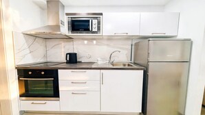 Eine kompakte Küche mit integriertem Mikrowellenherd, Backofen und Kühlschrank.