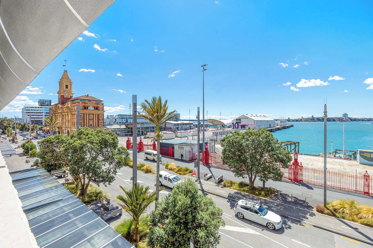 A coastal cityscape with a prominent clock tower, a marina, and modern buildings.
