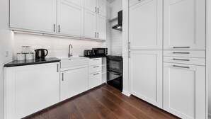 Een moderne keuken met witte kasten, een zwart aanrecht, een koffiezetapparaat, een magnetron en een oven.