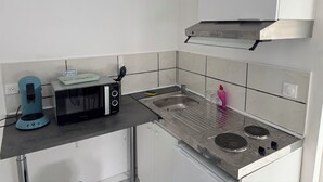 A compact kitchen with a microwave, toaster, and gas stove.