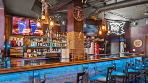 A bar with a wooden counter, bar stools, and a neon pirate sign. - Follow the Moon Villa, St Regis Oceanfront in Topsail (North Topsail Beach)