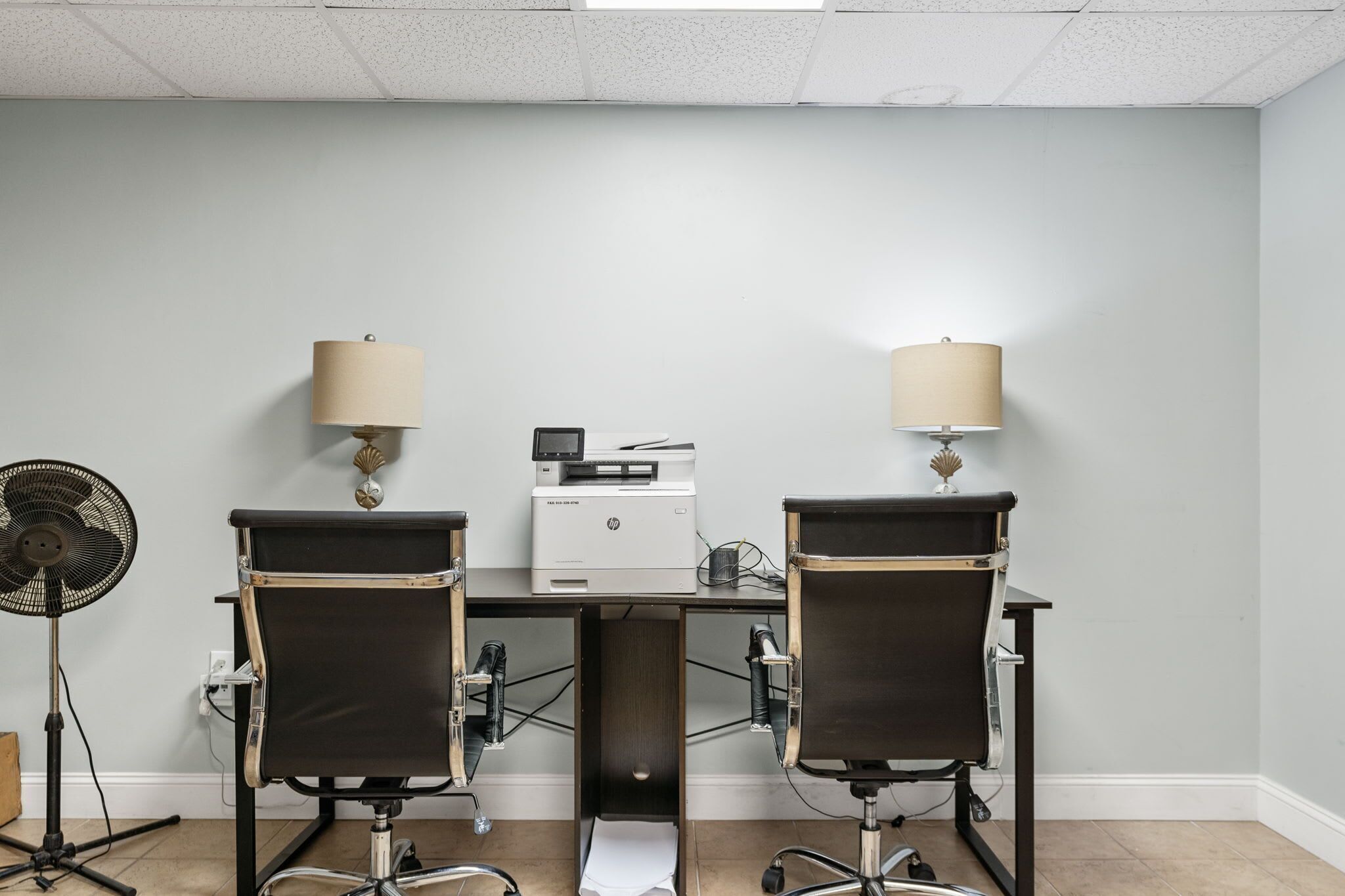 A conference room with two chairs, a printer, and two lamps.