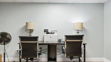 A conference room with two chairs, a printer, and two lamps.