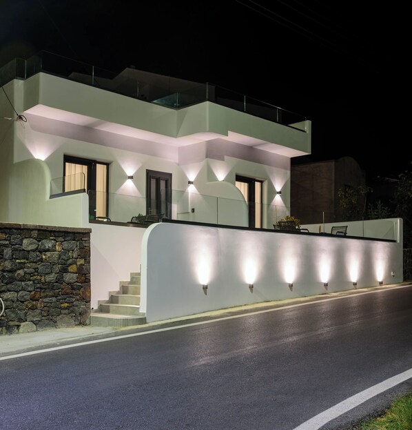 A modern two-story house with a stone facade, a balcony, and a well-lit entrance. - Casa della Liberta Firostefani (Santorini)