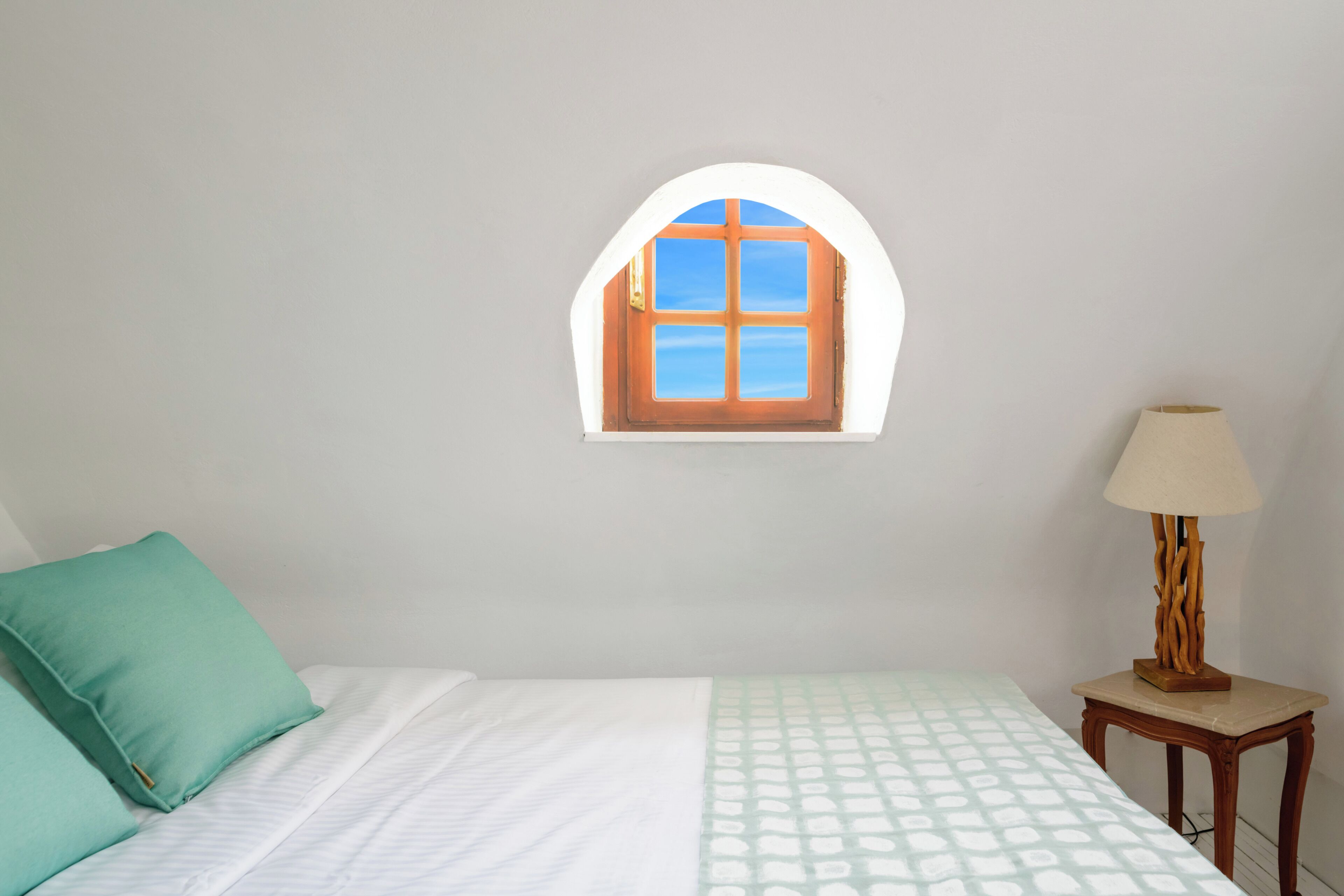 A bedroom with a single bed, a window with a view, and a bedside table with a lamp.