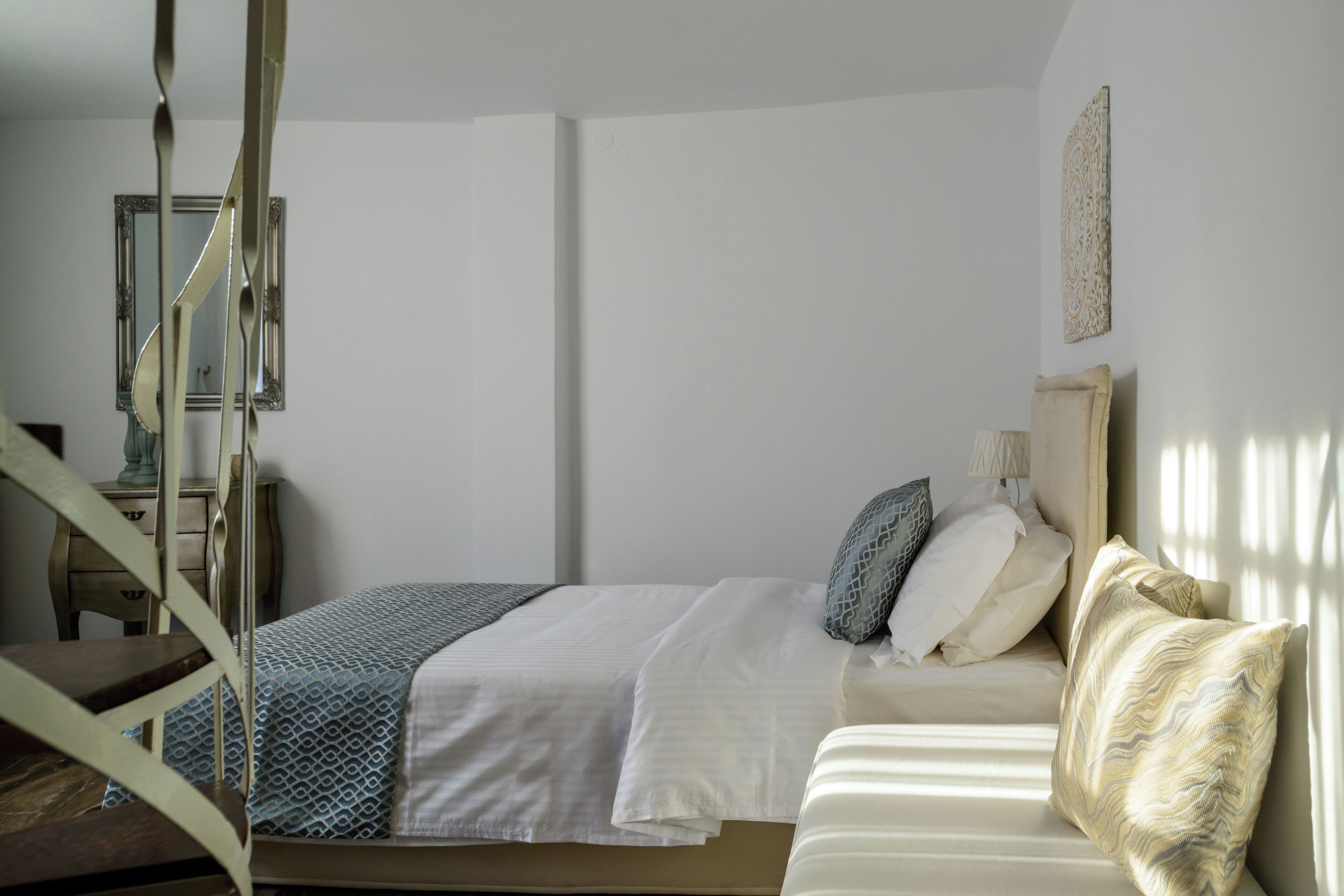 A bedroom with a bed, a chair, a dresser, and a mirror.
