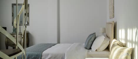 A bedroom with a bed, a chair, a dresser, and a mirror.