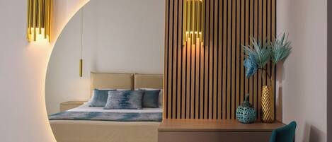 A modern bedroom with a curved wall, a bed, a desk with a chair, and decorative wall sconces.