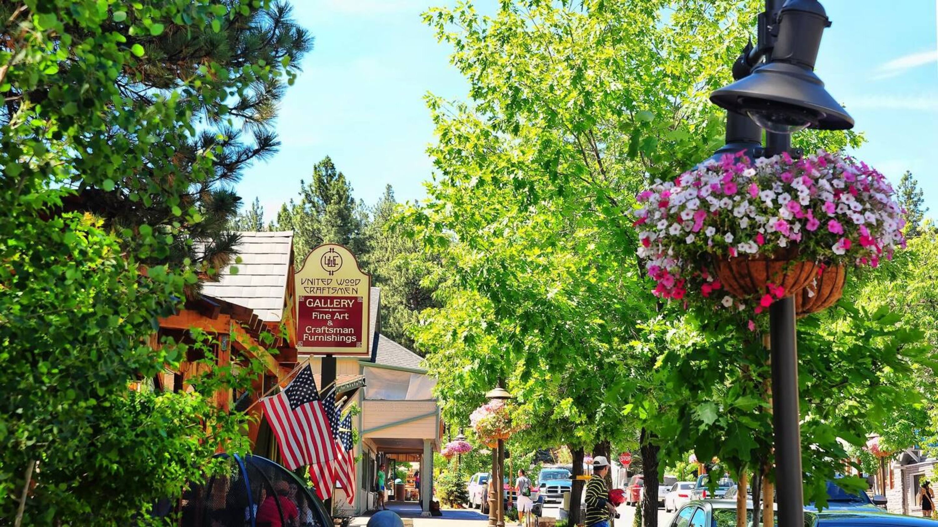 A street with a sign for United Wood Craftmen Gallery, Fine Art & Craftsman Furnishings, and American flags.