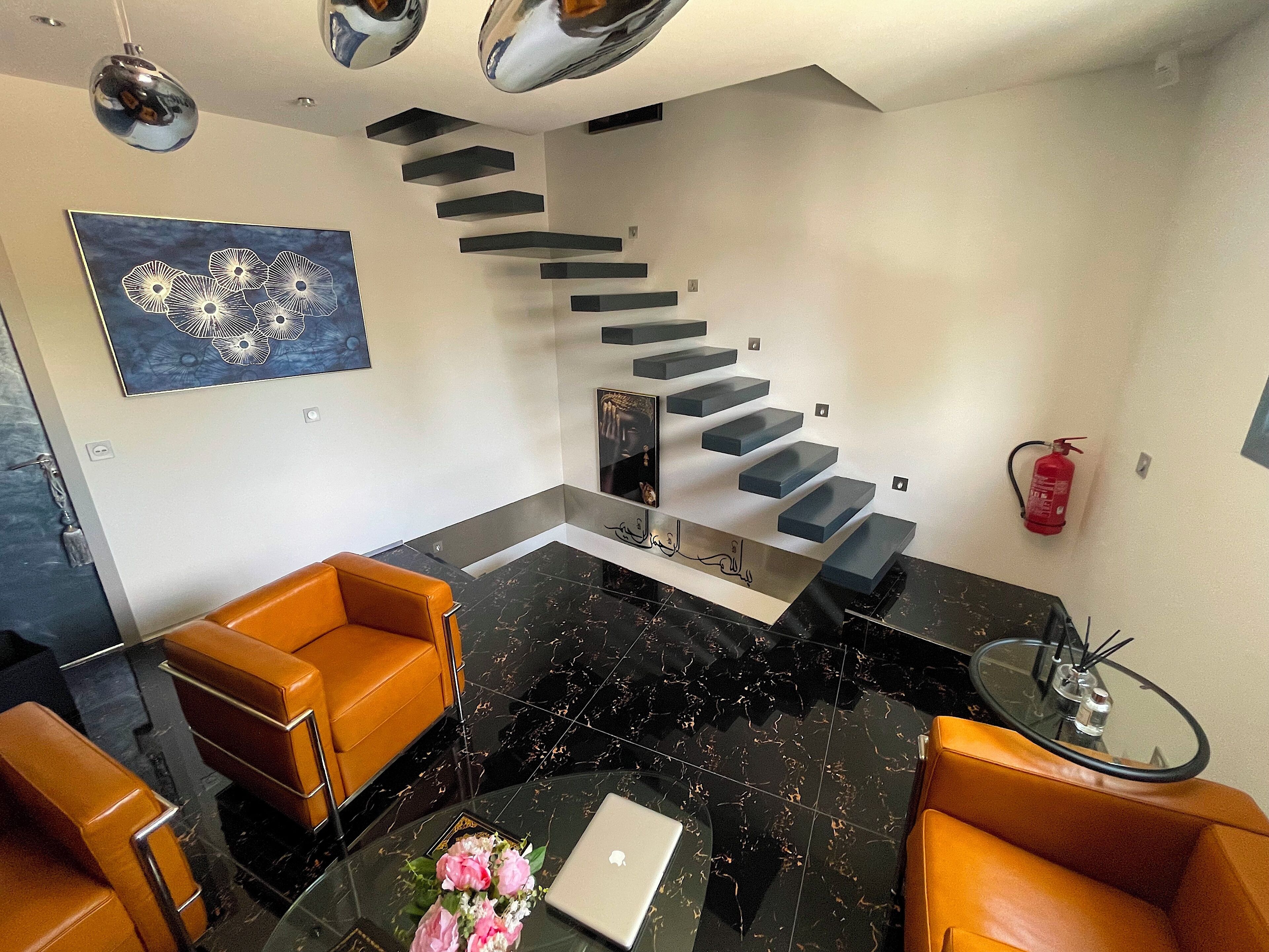 A modern living room with a black marble floor, a glass coffee table, and two leather sofas.