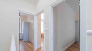A hallway with wooden flooring and white walls, leading to a room with a large window and a door. - Sleeps 10 few minutes' walk to Abbeywood Station (Gillingham)