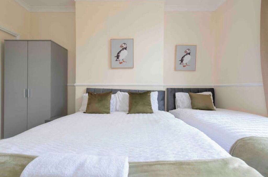Ein Hotelzimmer mit zwei Betten, einem Kleiderschrank und zwei gerahmten Bildern an der Wand.