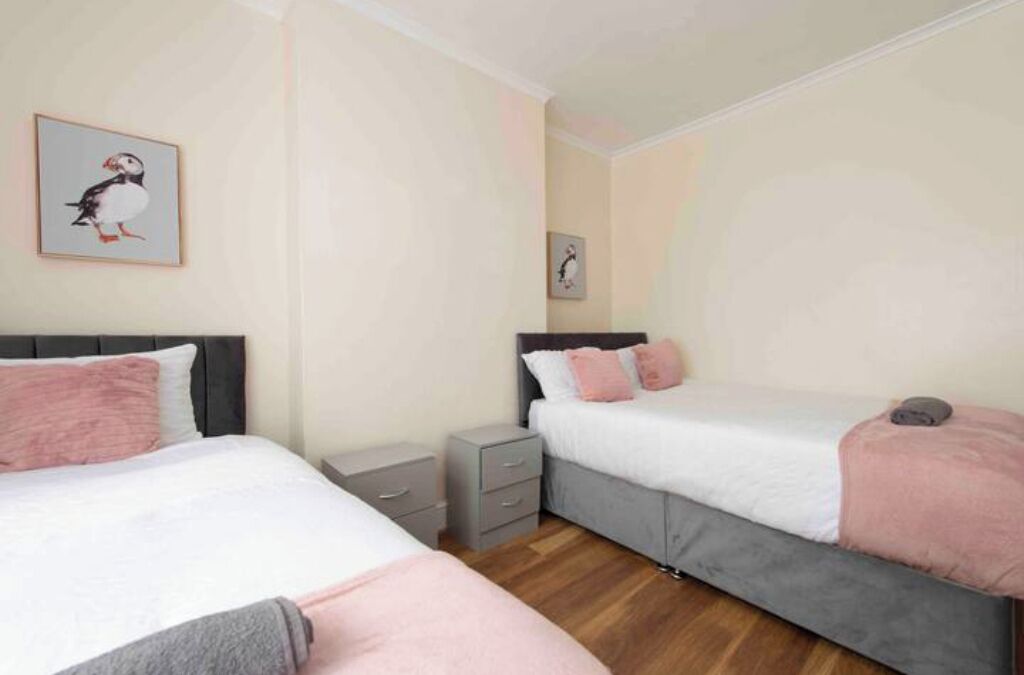 Een slaapkamer met twee bedden, een nachtkastje en een kleine ladekast.