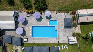 An aerial view of a pool area with a rectangular pool, multiple umbrellas, and outdoor seating. - Alba Marea (Dio-Olympos)