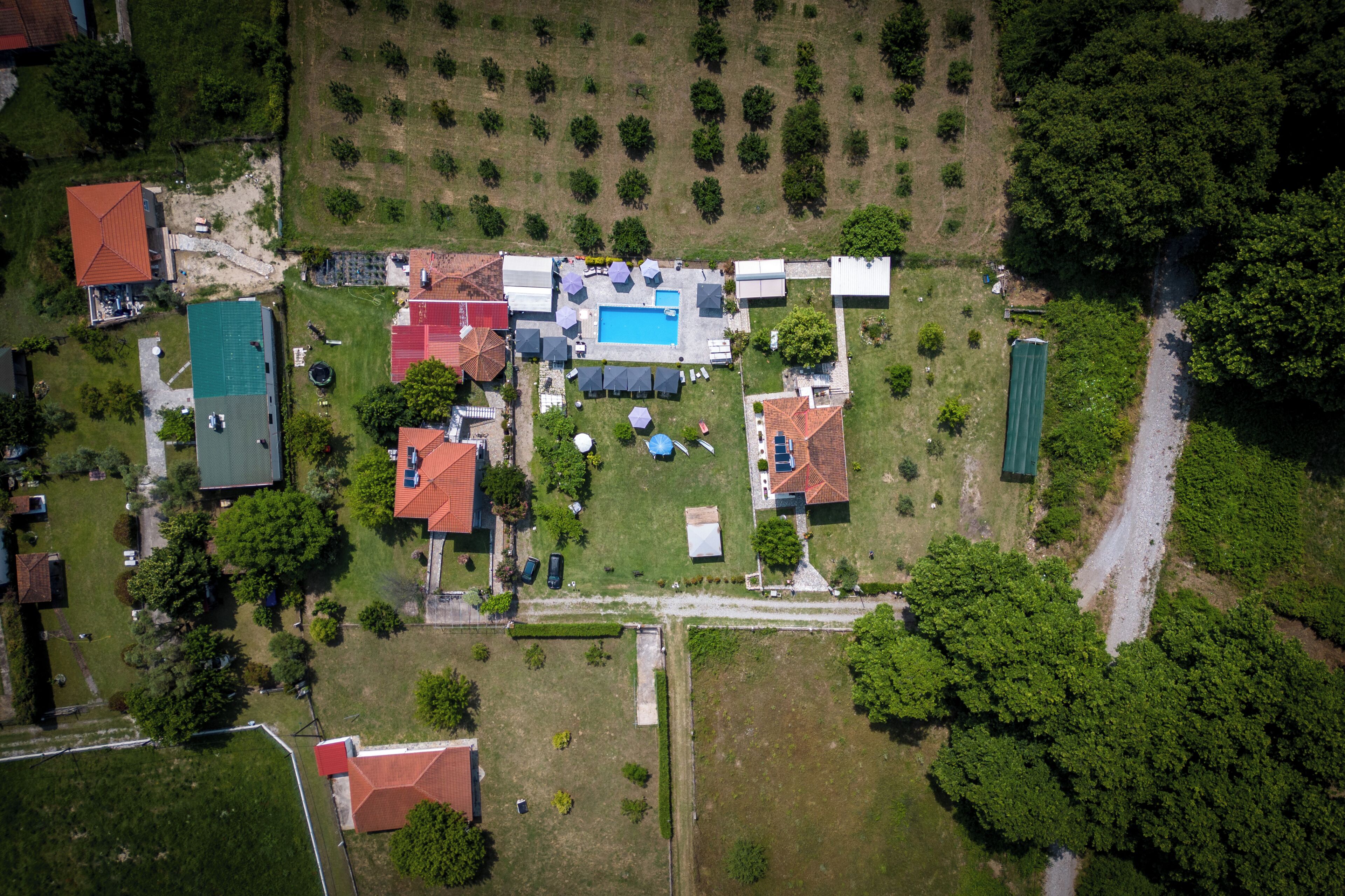 An aerial view of a residential area with multiple houses, a swimming pool, and a green field.