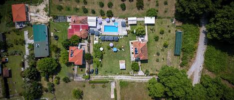 An aerial view of a residential area with multiple houses, a swimming pool, and a green field.
