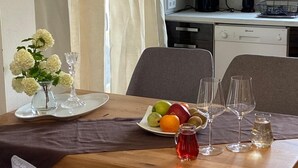A dining area with a wooden table set for four, a vase of white flowers, and a plate of fruit. - Alba Marea (Dio-Olympos)