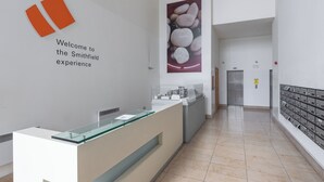A reception area with a glass partition, a welcome sign, a poster of stones, and a row of mailboxes. - 2-bedroom apartment in charming Smithfield Market with Parking (Dublin)