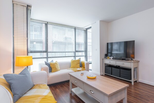 A modern living room with a sofa, a coffee table, a TV, and a lamp.