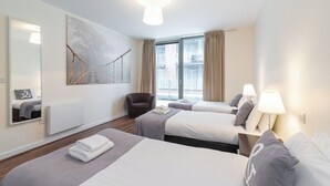 A hotel room with two beds, a large mirror, a window with curtains, and a wall-mounted artwork. - 2-bedroom apartment in charming Smithfield Market with Parking (Dublin)