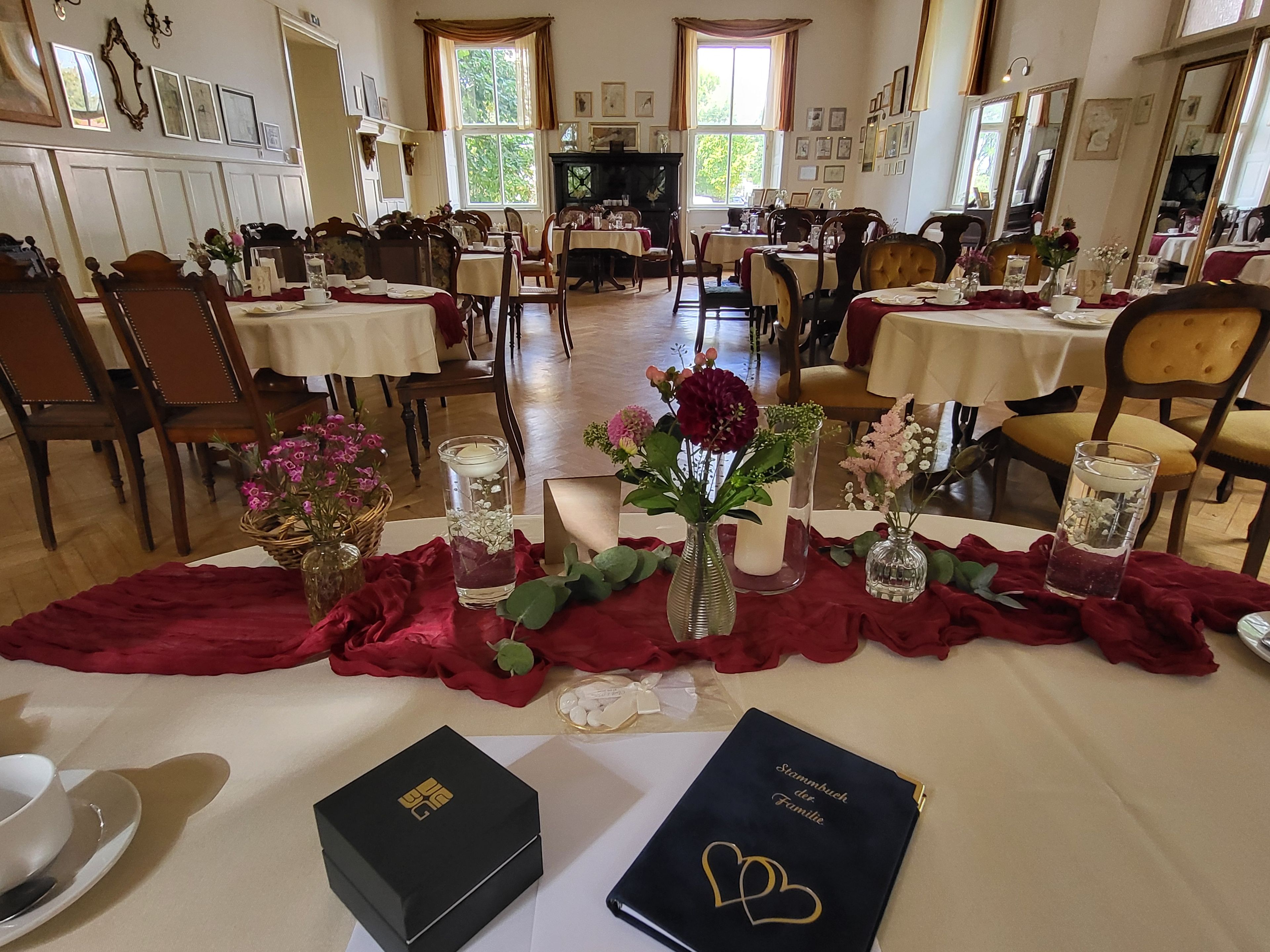 A dining area with tables set for a meal, surrounded by chairs, and decorated with flowers and candles.