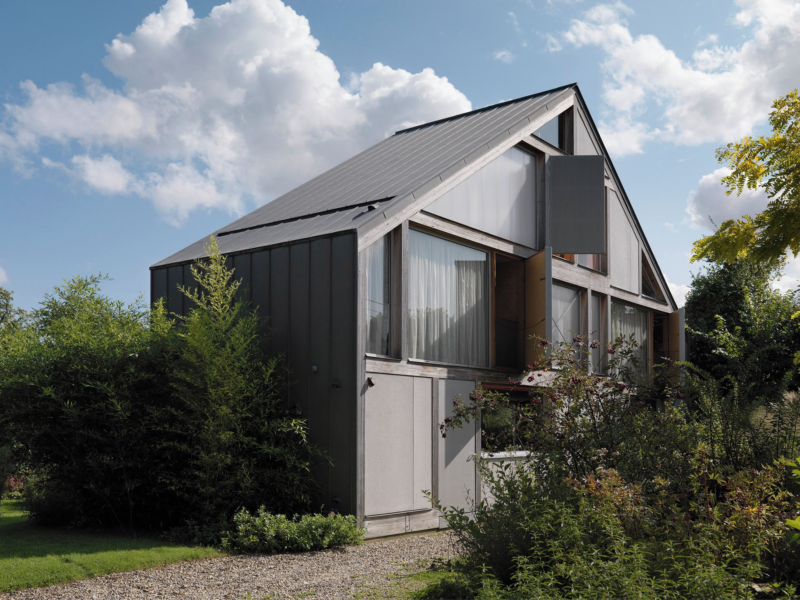 Ein modernes Haus mit Satteldach, großen Fenstern und einem Garten.