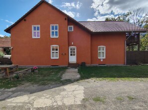 Una casa de dos pisos con fachada roja, una puerta principal y varias ventanas.