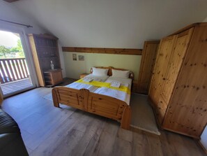 Ein Schlafzimmer mit einem hölzernen Bett, einem Schrank und Blick ins Freie.