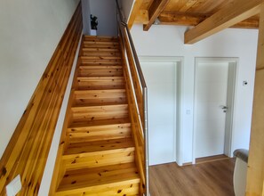 A wooden staircase with a handrail, leading to a white door at the top.