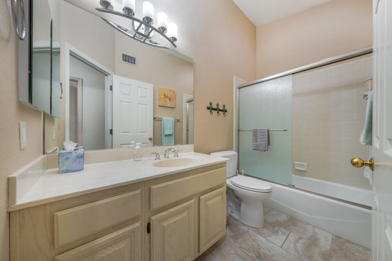 A bathroom with a vanity, sink, mirror, toilet, and shower.