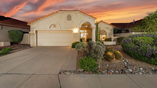 A two-story house with a garage, surrounded by landscaped gardens and cacti.