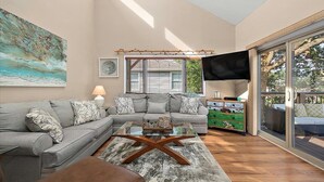 A living room with a grey sofa, a glass coffee table, and a TV on a stand. - Quiet Waterfront Getaway in North Ocean City (Ocean City)