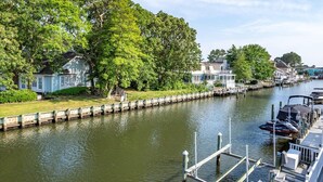 A canal with houses on one side and a dock with boats on the other. - Quiet Waterfront Getaway in North Ocean City (Ocean City)