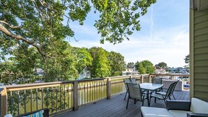 A deck with outdoor furniture, a railing, and a view of a river and buildings. - Quiet Waterfront Getaway in North Ocean City (Ocean City)