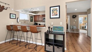 A modern kitchen with a bar area, wooden flooring, and a dining area with a view. - Quiet Waterfront Getaway in North Ocean City (Ocean City)