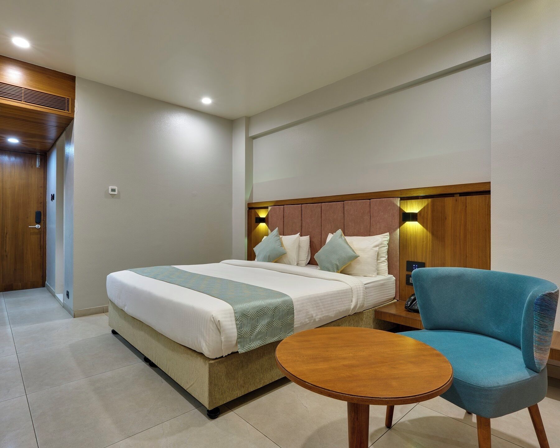 Une chambre d’hôtel avec un lit, une table de chevet, une chaise et une petite table ronde.
