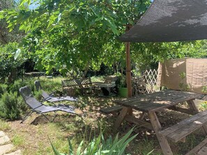 Eine Holzterrasse mit Tisch und Stühlen, umgeben von üppigem Grün und Bäumen.