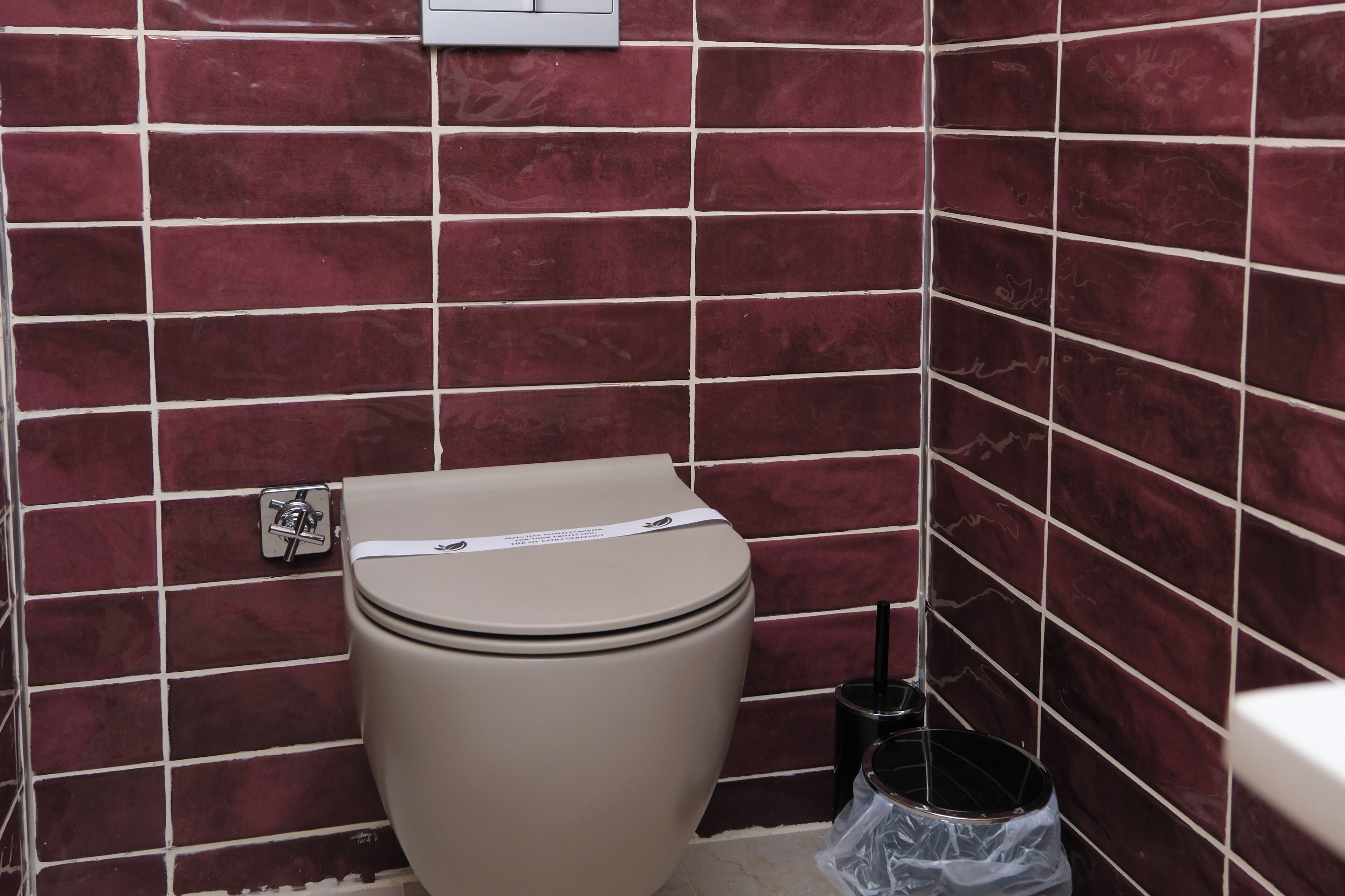 Bagno con un water, un cestino e una presa elettrica a muro.