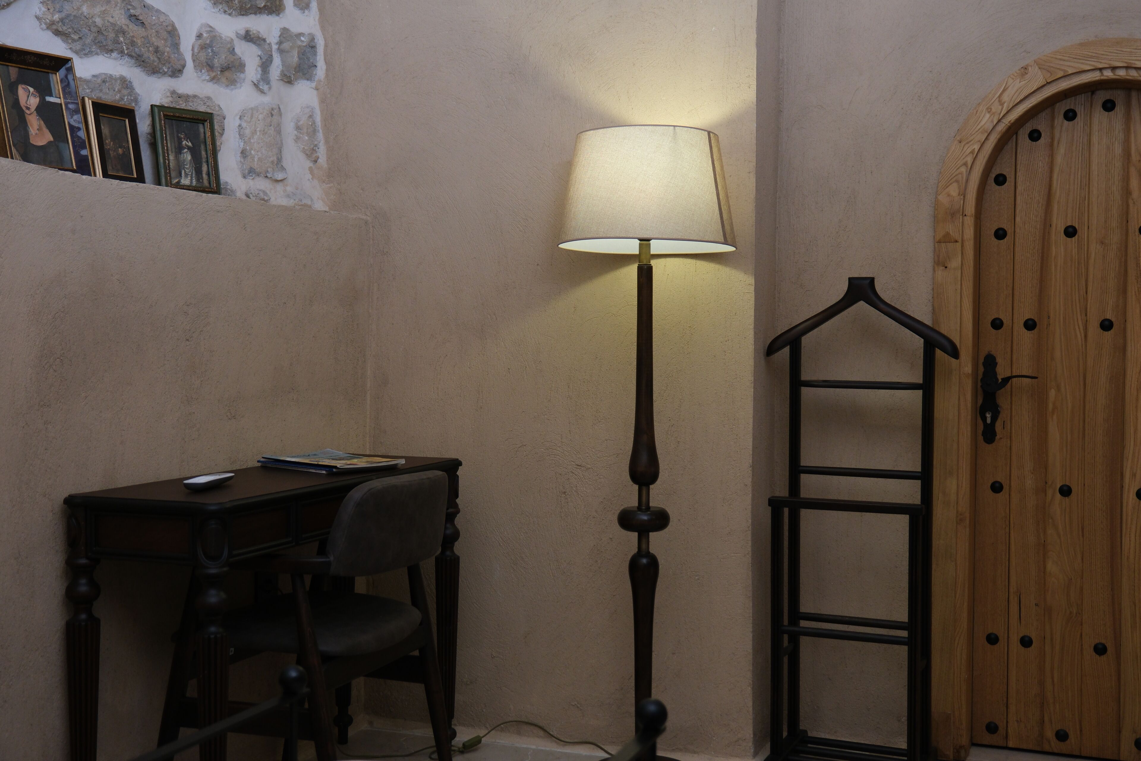 Una habitación con escritorio, silla, lámpara y puerta de madera.