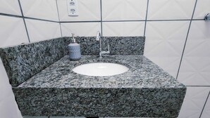 Ein Badezimmer mit einem Granittisch, einem Wasserhahn und einer Seifenspender.