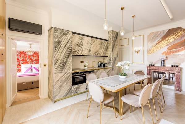 Une cuisine moderne avec un dosseret en marbre, un coin repas avec une table et des chaises en marbre, et une cheminée agrémentée d’objets décoratifs.