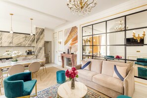 Un salon moderne avec un canapé beige, des fauteuils turquoise, une table basse et un grand miroir.