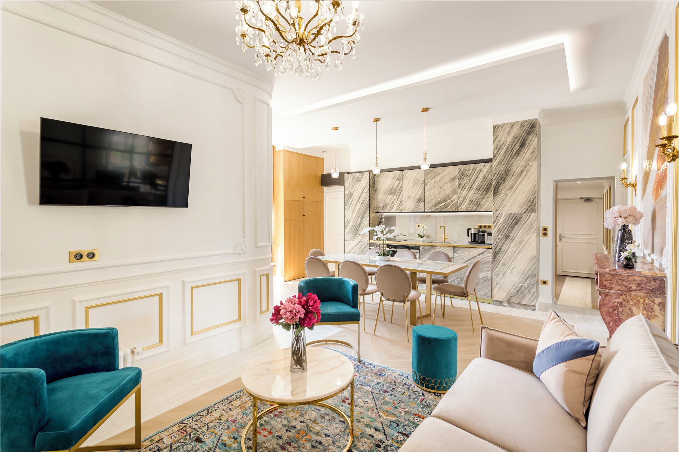 A modern living room with a TV, teal armchairs, a coffee table, and a sofa.