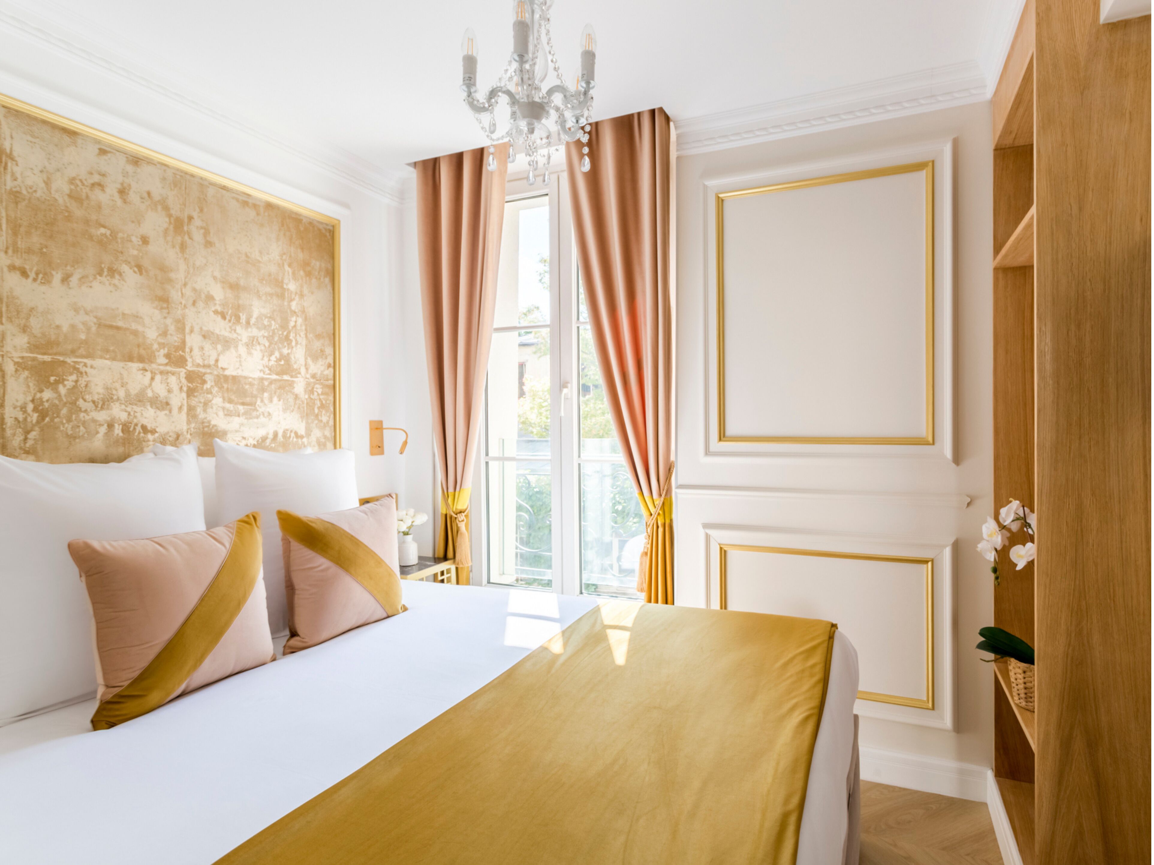 Une chambre d’hôtel avec un grand lit, un lustre et une vue sur l’extérieur.