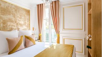 A hotel room with a large bed, a chandelier, and a view of the outdoors.