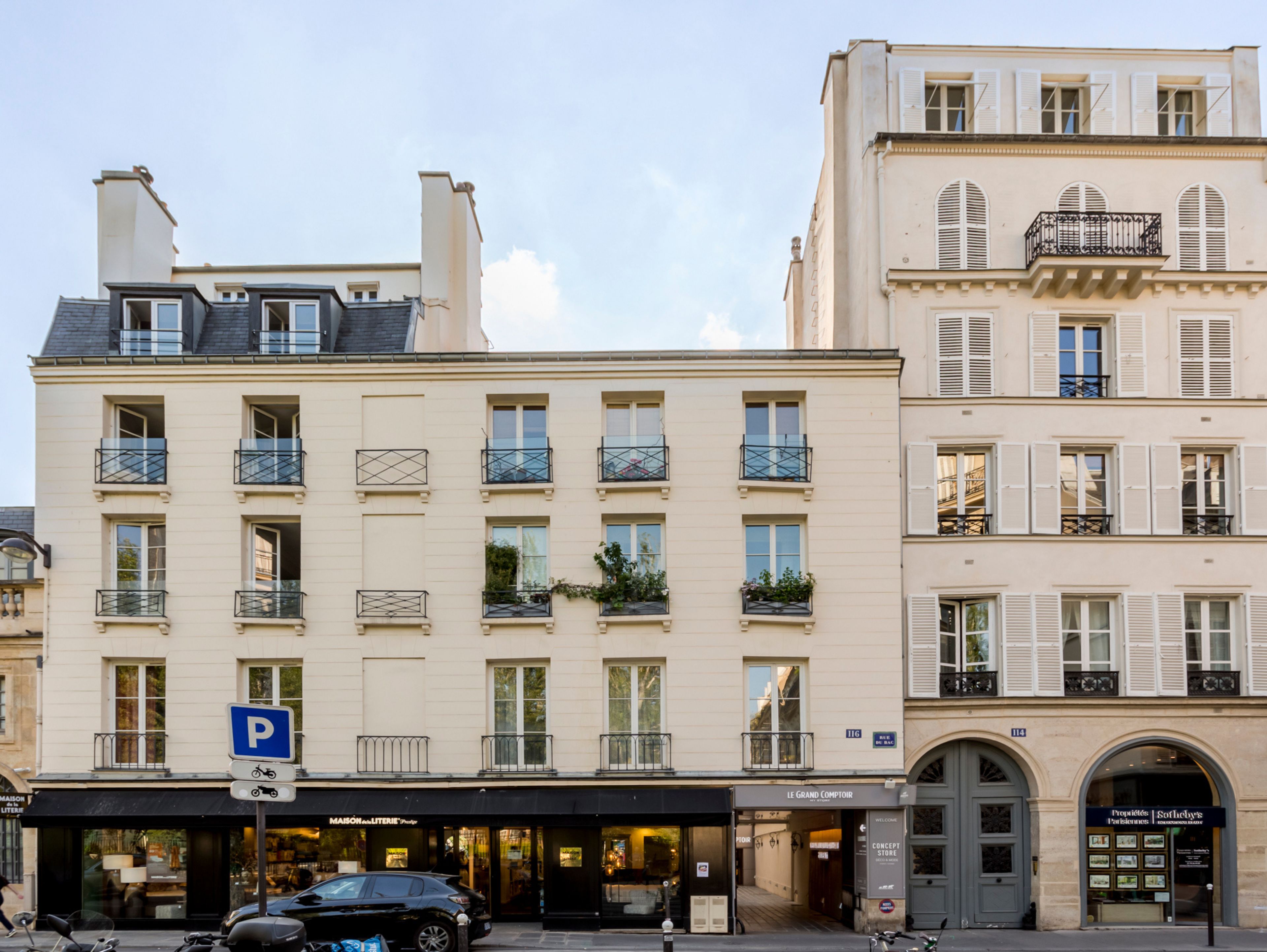 A multi-story building with a ground-floor shop and a parking sign.
