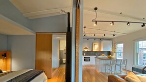 A modern apartment with a bedroom, living area, and kitchen.